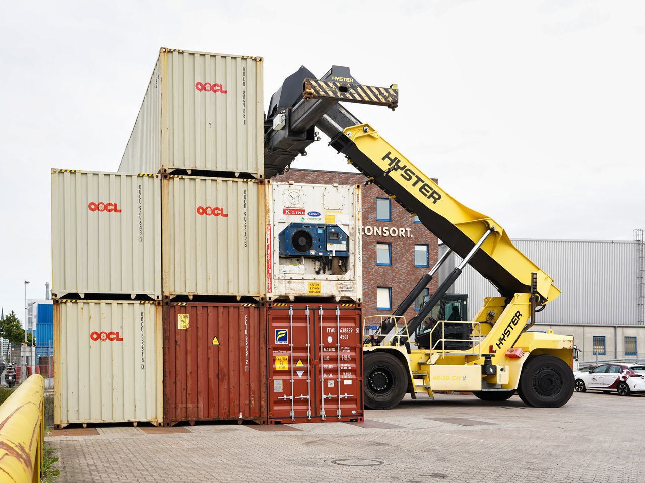 A container stacker organizing shipping containers at Hamburg port on a clear day.