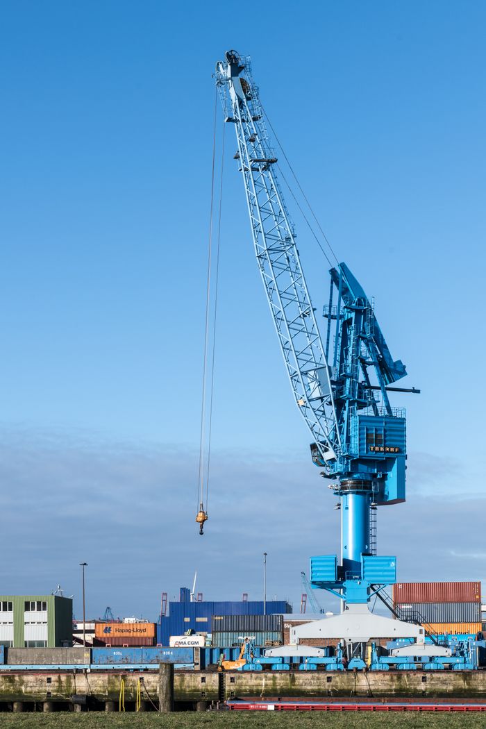 Blue crane at Hamburg port against a clear blue sky, showcasing global commerce.